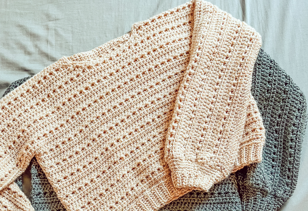 Two crochet sweaters are laid out flat to show texture. The pattern is a size-inclusive pullover crochet pattern