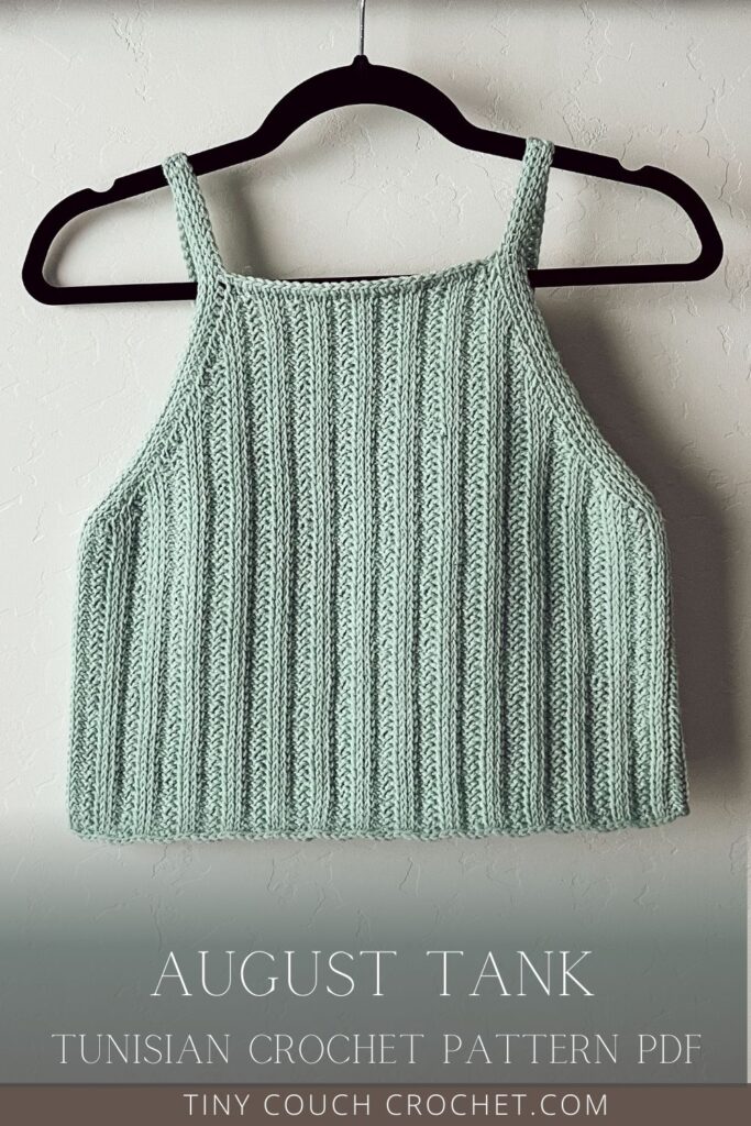 A hand-made seafoam green top made from this Tunisian crochet tank top pattern is hanging on a hanger against a wall. Text reads "August Tank, Tunisian Crochet Pattern PDF, tinycouchcrochet.com"